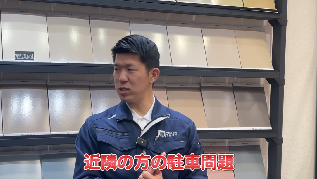 外壁塗装の専門スタッフが、足場設置時の工事車両による「近隣の方の駐車問題」というクレーム事例について解説している場面。道路使用許可の申請や、周辺住民への丁寧な事前説明といった対策の必要性を伝えている。