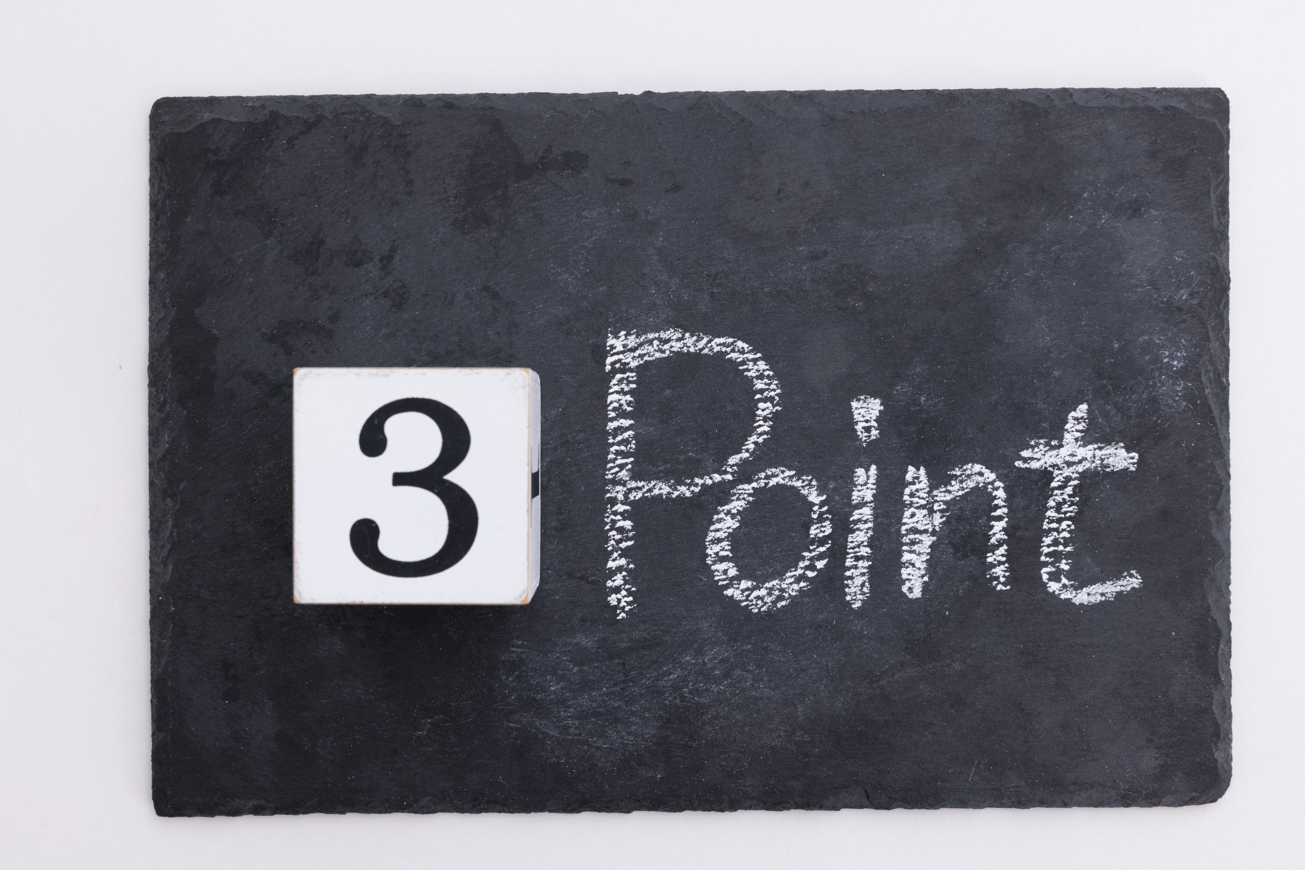 黒いスレートボード（石の板）の上に、数字の「3」が書かれた白いブロックと、チョークで書かれた「Point」という文字が置かれている。これは、外壁塗装の業者選びで失敗しないための「3つの注意点」や、悪徳業者が使う「危険なセールストーク3選」など、重要なポイントをリストアップする記事を象徴するイメージ。シンプルでおしゃれなデザインが、要点を分かりやすく伝えている。
