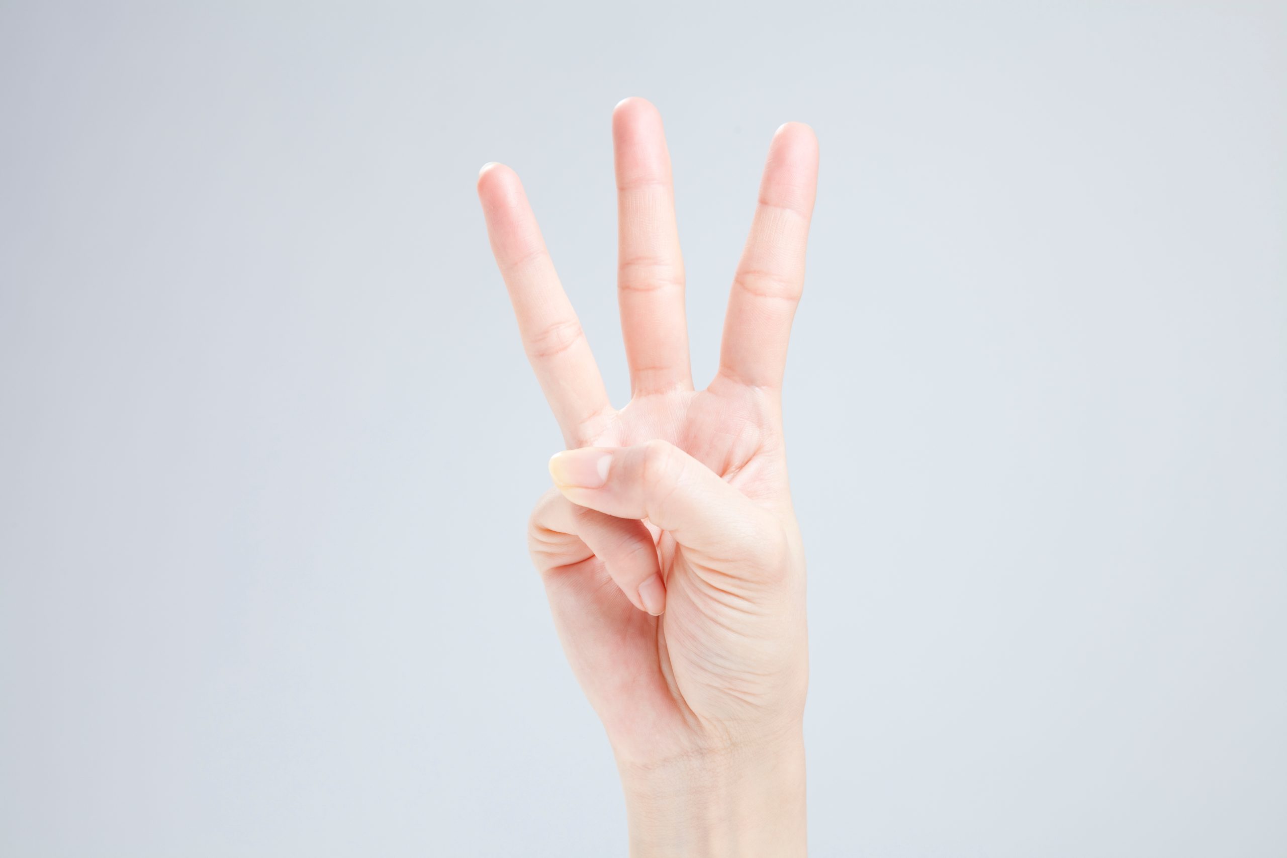明るい背景に3本の指（人差し指、中指、薬指）を立て、数字の「3」を示す手のクローズアップ。風水を取り入れた外壁塗装の色選びで後悔しないための「3つのコツ」や、外観を素敵にするためのポイントを象徴する、クリーンで分かりやすいイメージ。